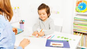 BCBA therapist guiding child during ABA therapy session using data collection and visual prompts to track progress